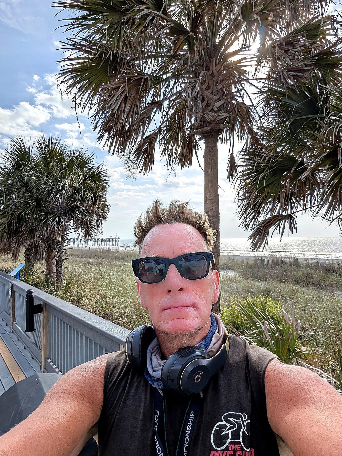 Real photo — enhanced: Coach RODA selfie on the Myrtle Beach boardwalk, palms, ocean, and pier behind him — Apr 22, 2025