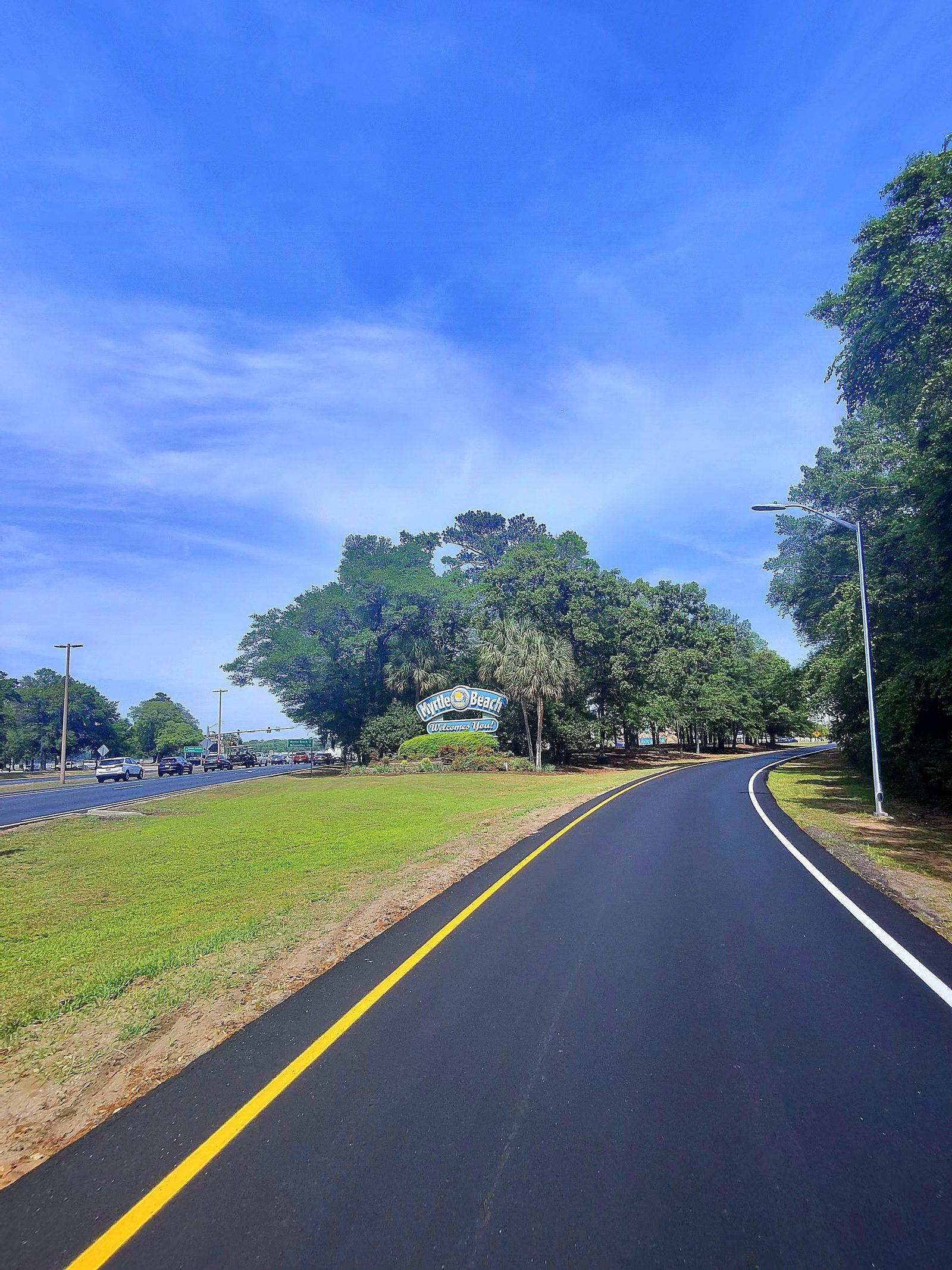 Real photo — enhanced: the road into Myrtle Beach, SC, the 'Myrtle Beach Welcomes You!' sign ahead — Apr 21, 2025