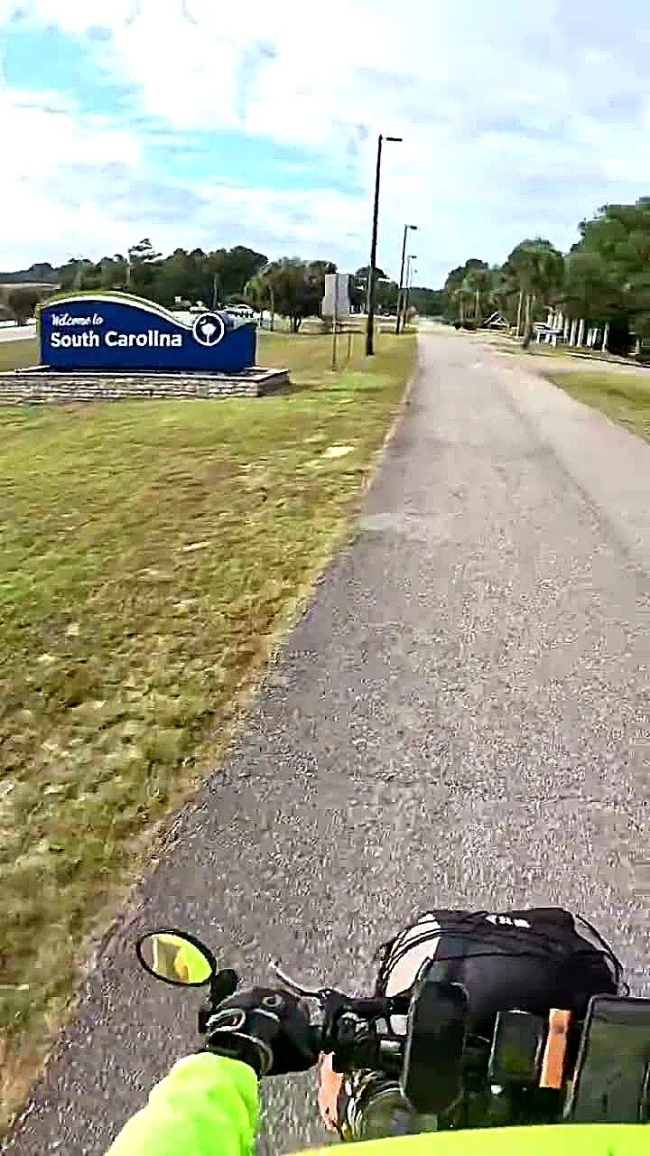 Real photo — enhanced: frame from Coach RODA's Oct 27, 2026 ride video, 26 seconds in — the 'Welcome to South Carolina' sign seen from the handlebars as he rolled into South Carolina